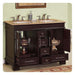 Dark wood bathroom vanity with marble top, double sinks, and decorative bronze urns inside open drawers.