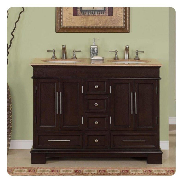 Dark wood bathroom vanity with double sinks, beige stone top, and decorative soap dispenser against sage green wall.