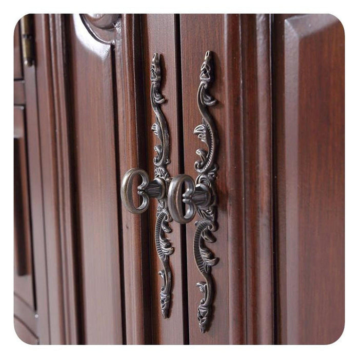 Ornate antique brass cabinet handles with scrollwork design on rich wooden cabinet doors, showing intricate vintage hardware.