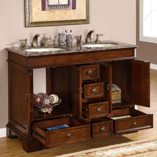 Wooden bathroom vanity with granite top, double sinks, bronze faucets, and multiple open drawers revealing storage space and decorative accessories.