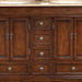 Rich mahogany bathroom vanity with raised panel doors, three small drawers in center, and four lower drawers, featuring antique bronze round drawer pulls.