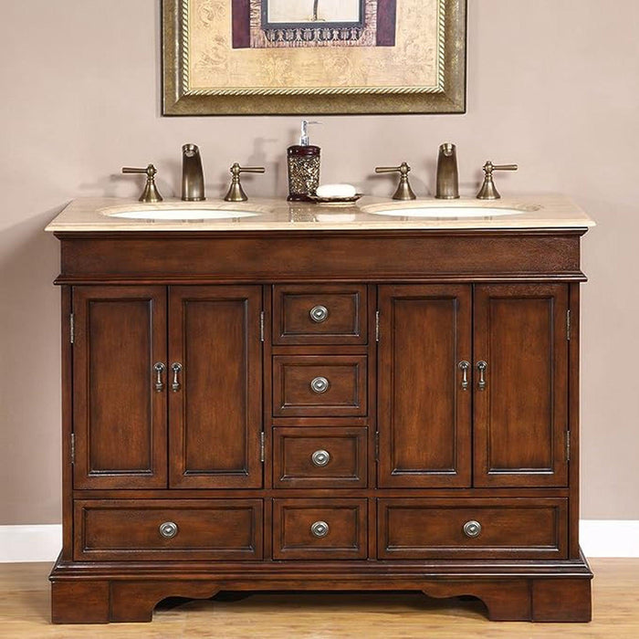 Traditional wooden bathroom vanity with dark brown finish, double sinks, marble countertop, and decorative bronze faucets and hardware.