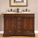 Traditional wooden bathroom vanity with dark brown finish, double sinks, marble countertop, and decorative bronze faucets and hardware.