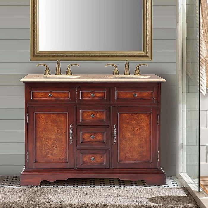 Cherry wood bathroom vanity with marble top, brass faucets, and gold-framed mirror against shiplap wall.