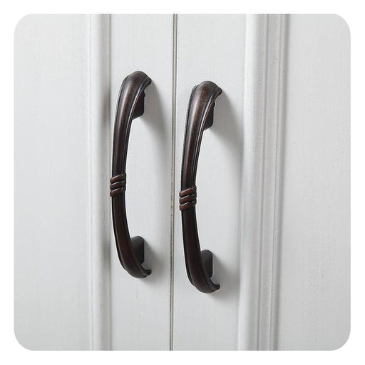 Two dark bronze curved cabinet handles on white paneled doors, with decorative twisted mid-section detailing.