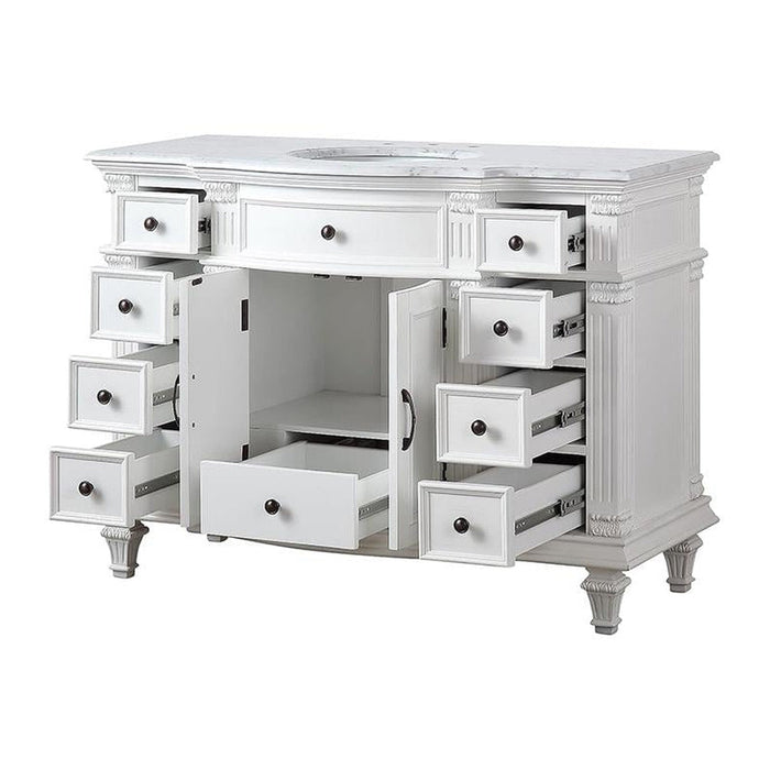 White vintage-style vanity with multiple open drawers, ornate carved details, and a marble-like top with sink cutout.