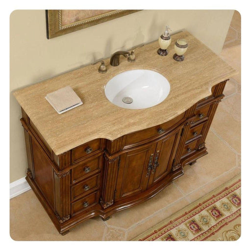 Elegant wooden bathroom vanity with curved design, travertine countertop, white sink, and ornate bronze fixtures.