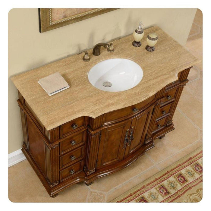 Elegant wooden bathroom vanity with curved design, travertine countertop, white sink, and ornate bronze fixtures.