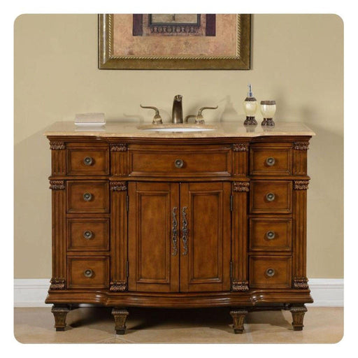 Elegant wooden bathroom vanity with ornate drawers, marble top sink, and decorative carved details, topped with bathroom accessories.