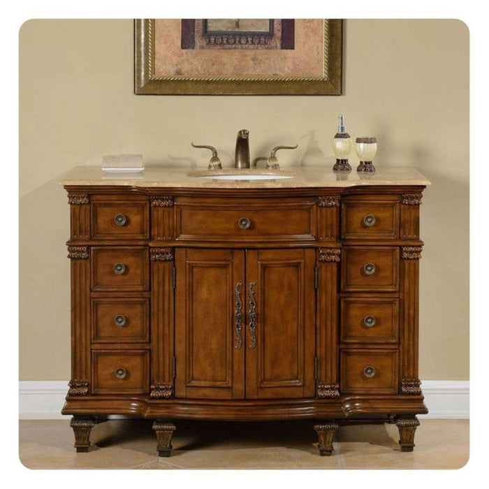 Elegant wooden bathroom vanity with ornate drawers, marble top sink, and decorative carved details, topped with bathroom accessories.