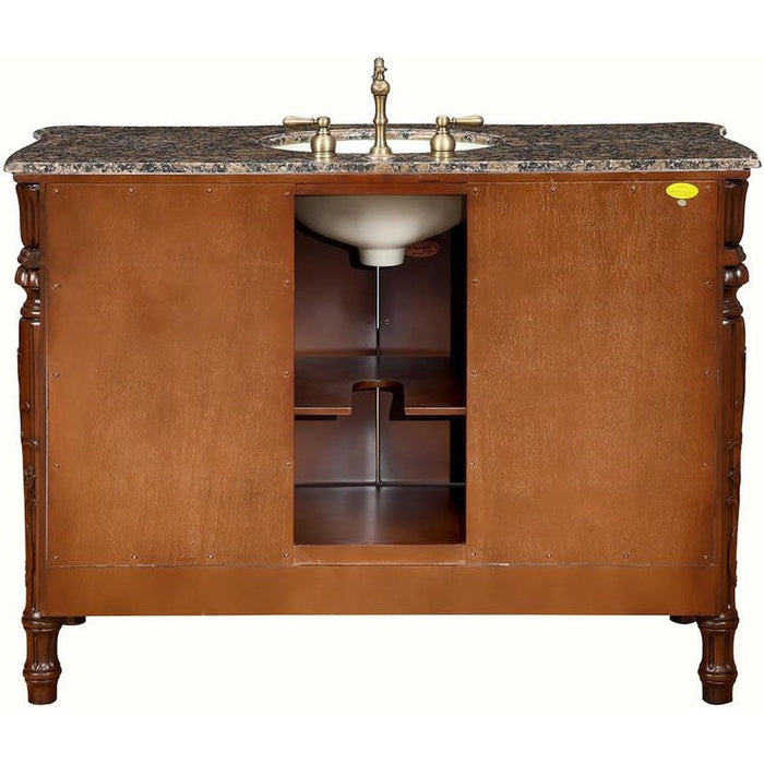 Elegant wooden bathroom vanity with marble countertop, oval sink, and brass faucet, featuring carved legs and interior shelving.
