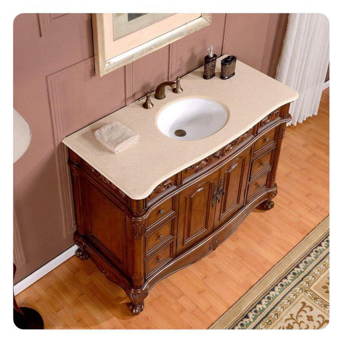 Elegant wooden vanity with curved legs, marble top sink, and ornate carved details in a pink-walled bathroom.