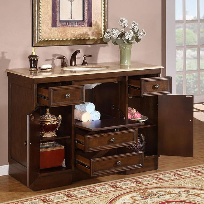 Dark wood bathroom vanity with marble top, open drawers revealing towels, decorative objects, and a vase of white flowers above.