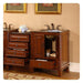 Rich wood bathroom vanity with granite top, ornate faucets, rolled towels, and open drawer revealing storage space.