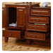 Rich cherry wood bathroom vanity with marble top, open cabinet door, and multiple drawers with round brass knobs