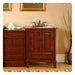 Cherry wood bathroom vanity with marble top, four drawers, double doors, bronze faucet, and rolled towels beside decorative plant.