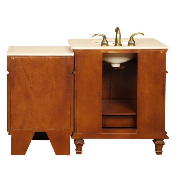 Wooden bathroom vanity with white marble top, brass faucets, and open cabinet storage on decorative legs.