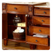 Elegant wooden dresser with ornate carved details, multiple drawers, and open shelving holding a woven basket of towels and an antique lamp.