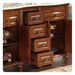 Polished wooden furniture with multiple open drawers, ornate hardware, and decorative turned legs on a patterned floor.