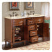 Classic wooden bathroom vanity with double sinks, marble top, ornate faucets, and open drawers revealing decorative shelving and accessories.