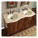 Elegant wooden double vanity with curved design, cream countertop, two sinks, and vintage bronze fixtures, with decorative rug and framed artwork.
