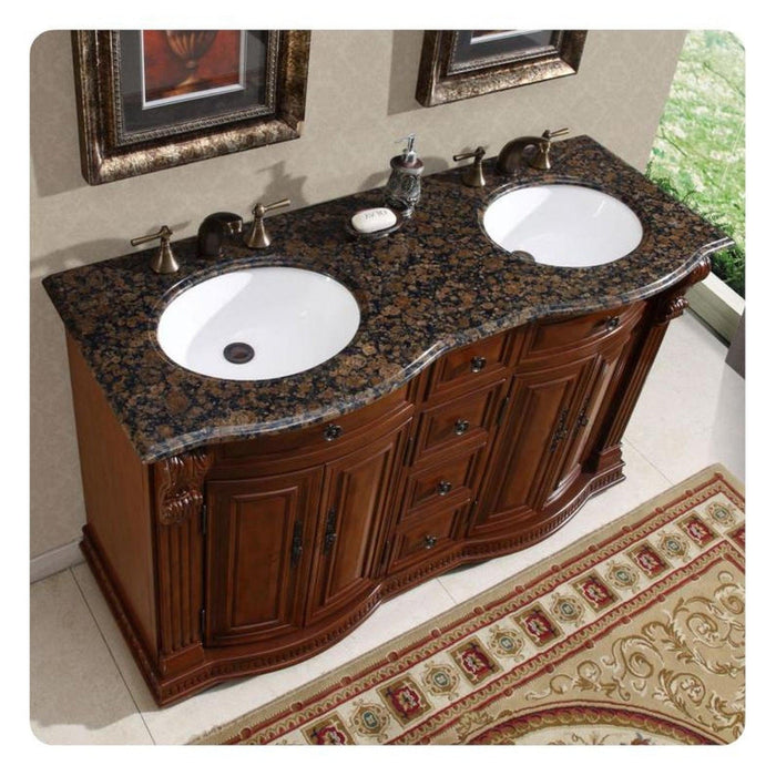 Rich wood bathroom vanity with Baltic brown granite top, double white sinks and ornate bronze faucets.
