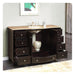 Dark wood bathroom vanity with multiple drawers, travertine countertop, and built-in sink with decorative ceramic vase