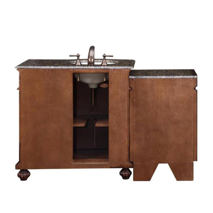 Wooden bathroom vanity with granite top, open cabinet doors revealing sink, and ornate round feet.