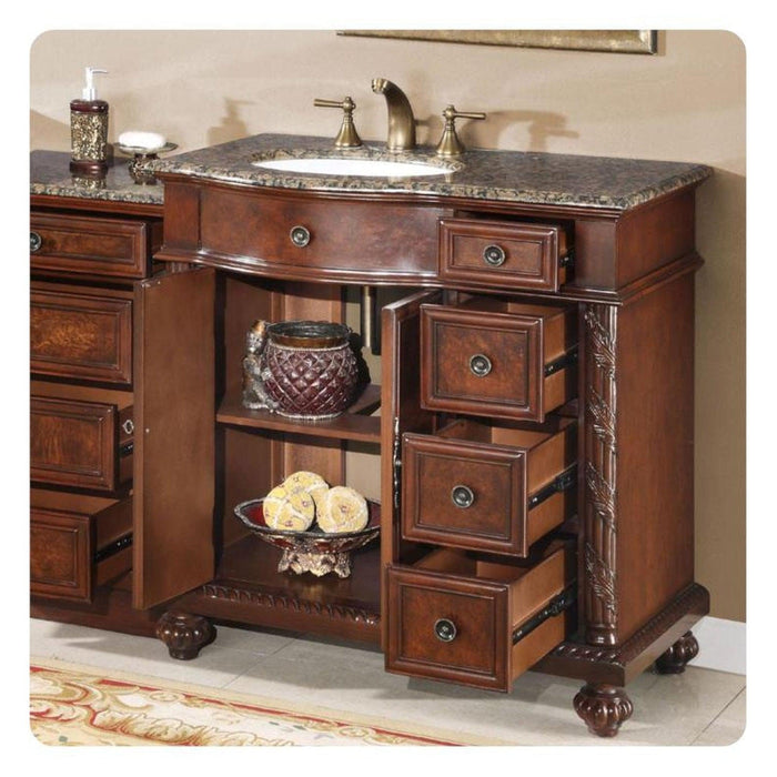Rich wood bathroom vanity with granite top, decorative drawers open, displaying ornate basket and lemons.