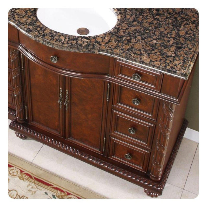 Ornate wooden bathroom vanity with Baltic brown granite top, carved details, and decorative brass hardware