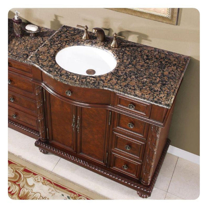 Elegant wooden bathroom vanity with Baltic brown granite countertop, white sink, and ornate carved details.
