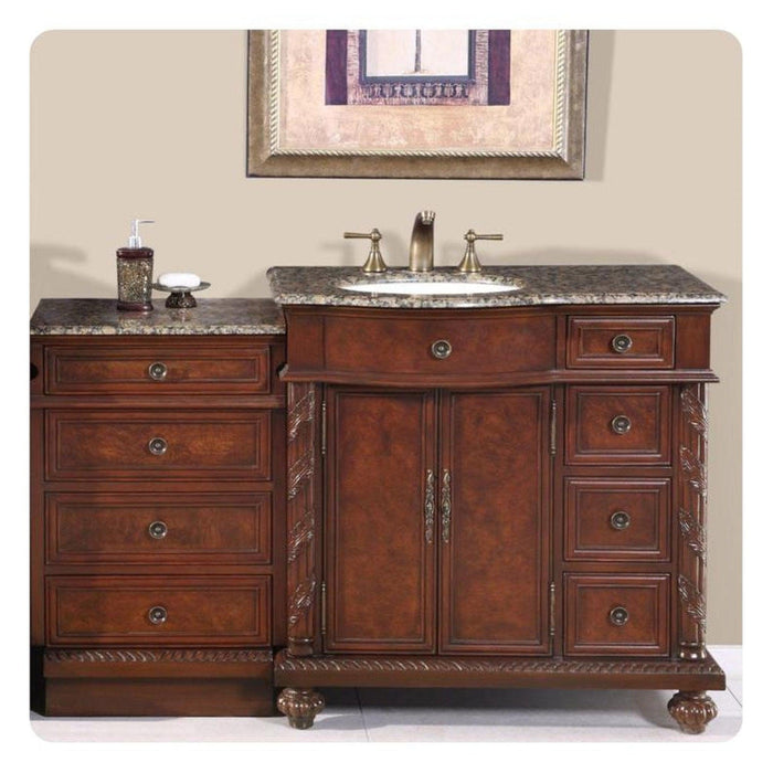 Elegant wooden bathroom vanity with dark granite top, multiple drawers, central cabinet, and oval sink with bronze faucet fixtures.