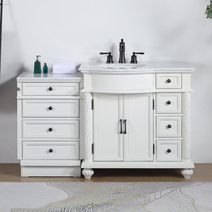 White bathroom vanity with marble top, black fixtures, four drawers, and central cabinet, styled with green soap dispensers and white towel.