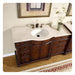 Elegant wooden bathroom vanity with white marble top, ornate dark wood cabinetry, bronze faucet, and small vase of delicate flowers.