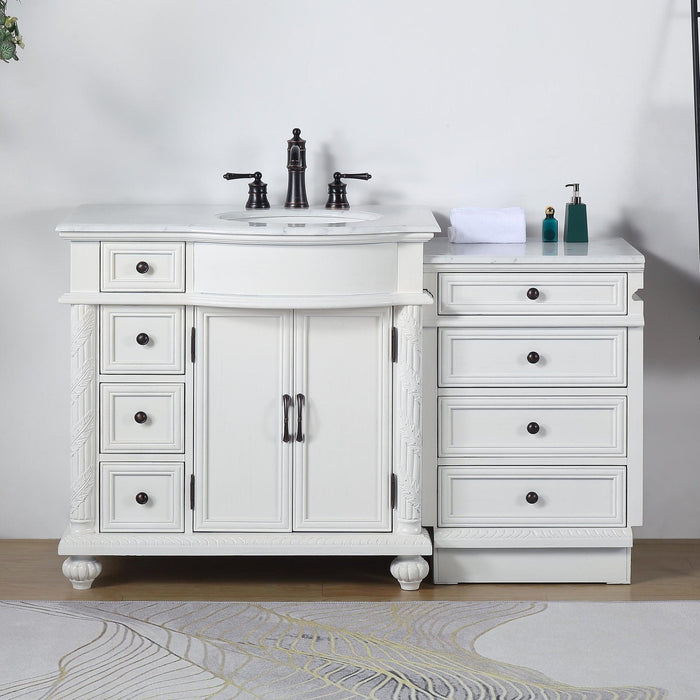 White bathroom vanity with black fixtures, featuring double cabinets, multiple drawers, and a marble-style countertop with decorative bottles and folded towel.