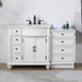 White bathroom vanity with black fixtures, featuring double cabinets, multiple drawers, and a marble-style countertop with decorative bottles and folded towel.