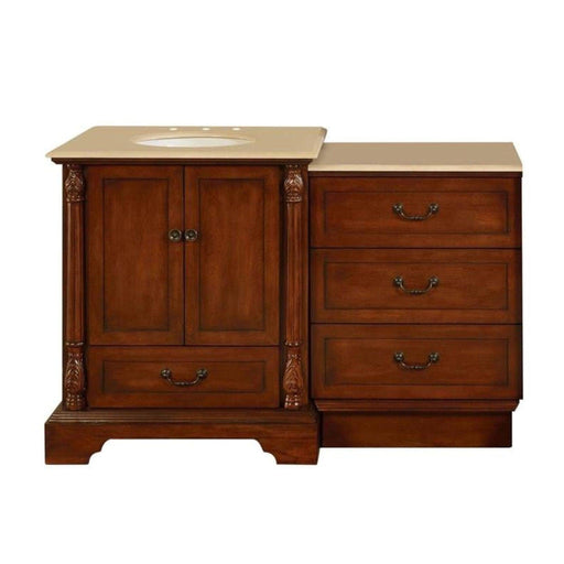 Traditional wooden bathroom vanity with ornate carved columns, beige stone top, and three drawers with antique handles.