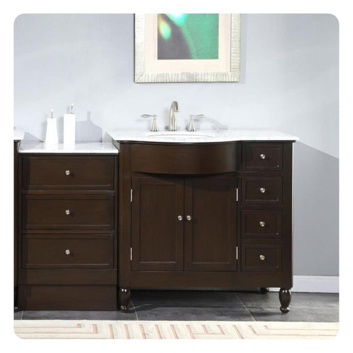 Dark wood bathroom vanity with white marble top, centered sink, and decorative chrome faucet and hardware