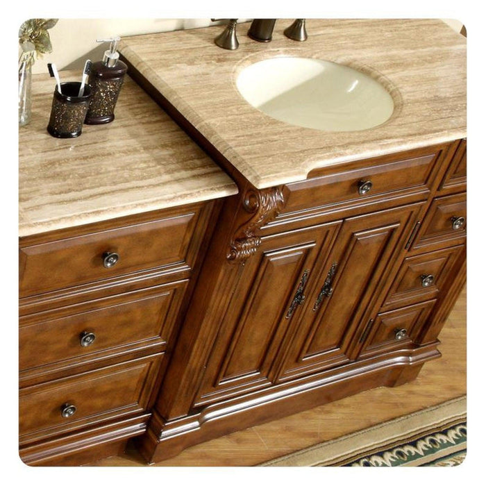 Rich wood bathroom vanity with carved details, marble countertop, and oval undermount sink with decorative accessories.