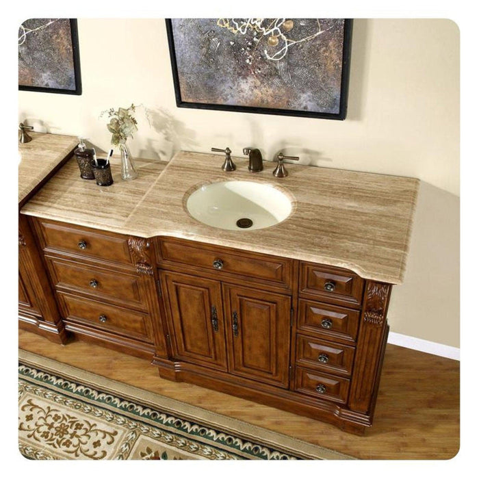 Wooden bathroom vanity with marble countertop, white sink, bronze fixtures, and decorative artwork hanging above.