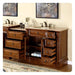 Rich wood bathroom vanity with multiple drawers open, revealing storage space and rolled towels, with marble countertop and bronze faucets.