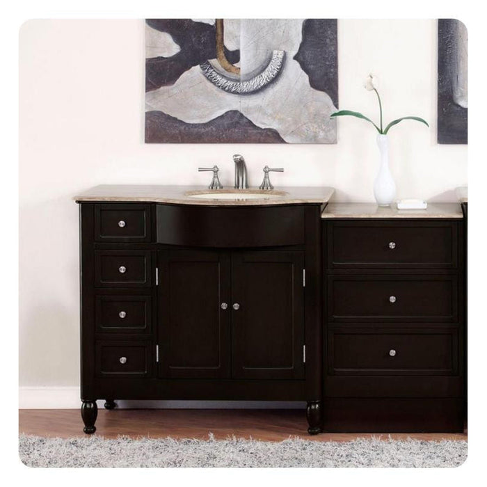 Dark wood bathroom vanity with marble top, single sink, and matching side cabinet, with abstract art and white vase with flower in background.