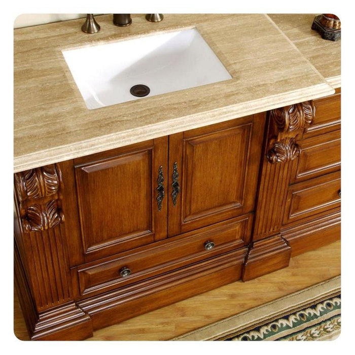 Ornate wooden bathroom vanity with carved details, marble countertop, and white undermount sink with bronze fixtures.