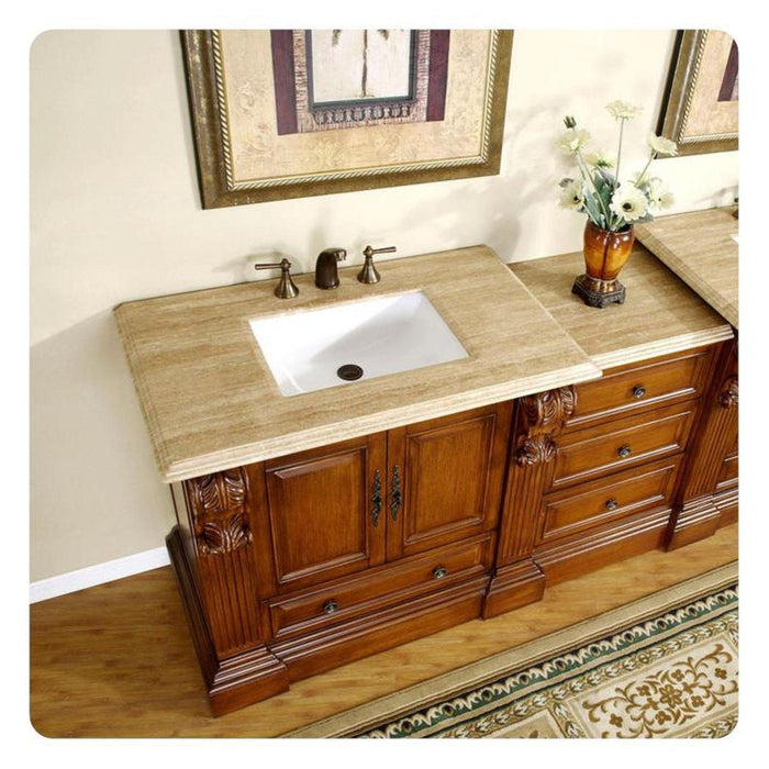 Elegant wooden bathroom vanity with marble countertop, white sink, bronze fixtures, and decorative floral vase.
