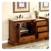 Elegant wooden bathroom vanity with marble countertop, ornate carved details, open cabinet door, and decorative vase with white flowers
