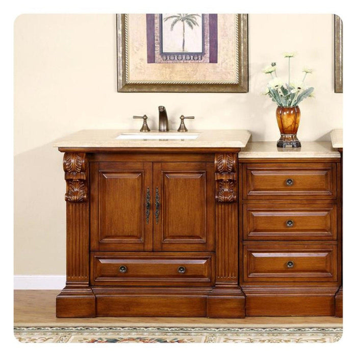 Elegant wooden bathroom vanity with carved details, marble top, sink, decorative vase with white flowers, and framed palm tree artwork.