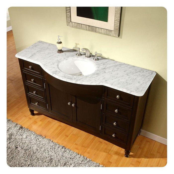 Dark wood bathroom vanity with white marble top, oval sink, and polished chrome fixtures, sitting on wooden floor with shag rug.