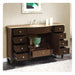 Dark wood bathroom vanity with multiple open drawers, marble top sink, and green decorative vase centered in open cabinet space