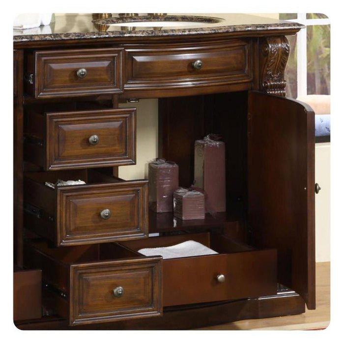 Dark wood bathroom vanity with marble top, multiple drawers, and burgundy candles displayed in open cabinet section.