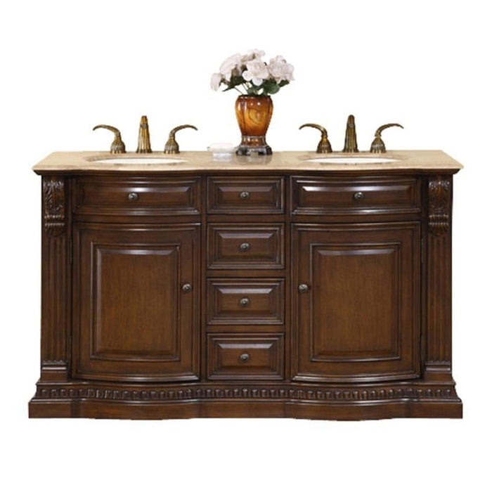 Rich wood bathroom vanity with marble top, two sinks, decorative hardware, and white flowers in amber vase.